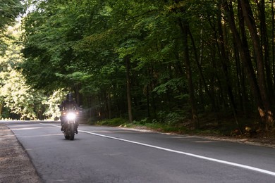 Photo of Young man in helmet driving modern motorcycle outdoors. Space for text