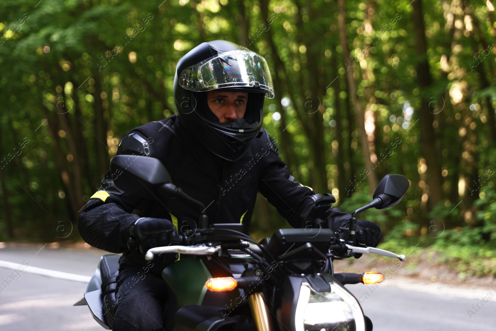 Photo of Young man in helmet driving modern motorcycle outdoors