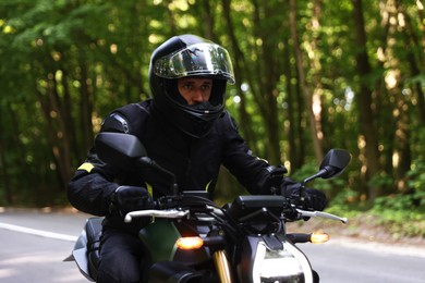 Photo of Young man in helmet driving modern motorcycle outdoors