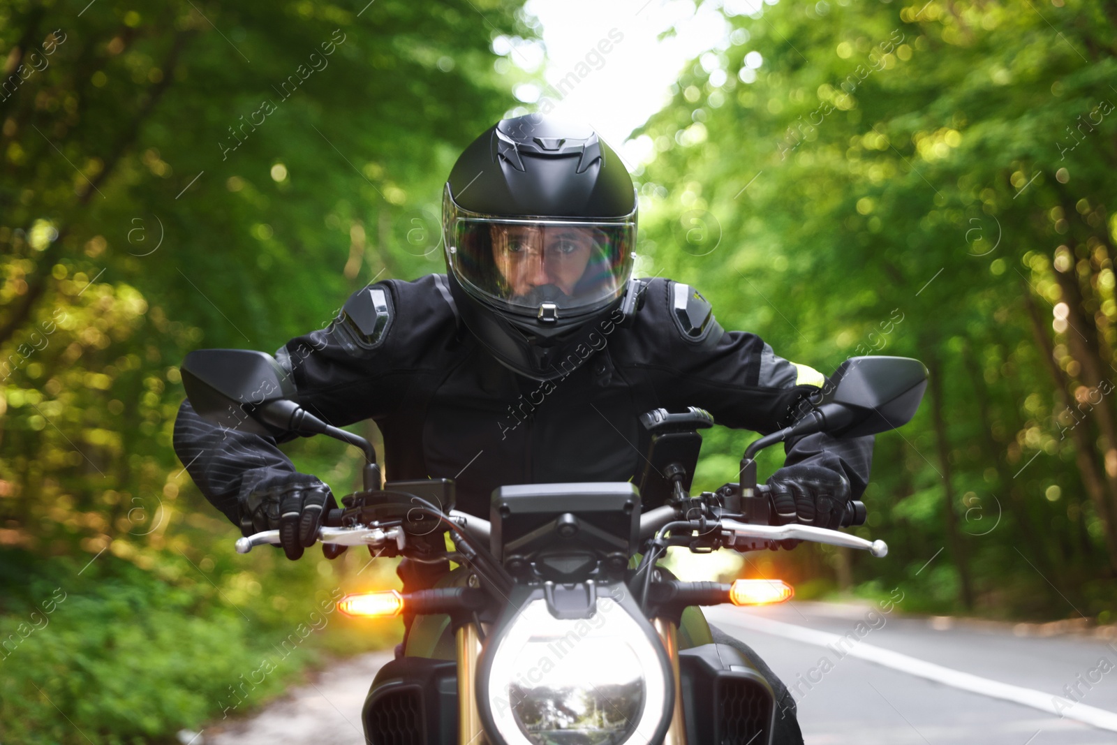 Young man in helmet driving modern motorcycle outdoors Photo of Young man in helmet driving modern motorcycle outdoors