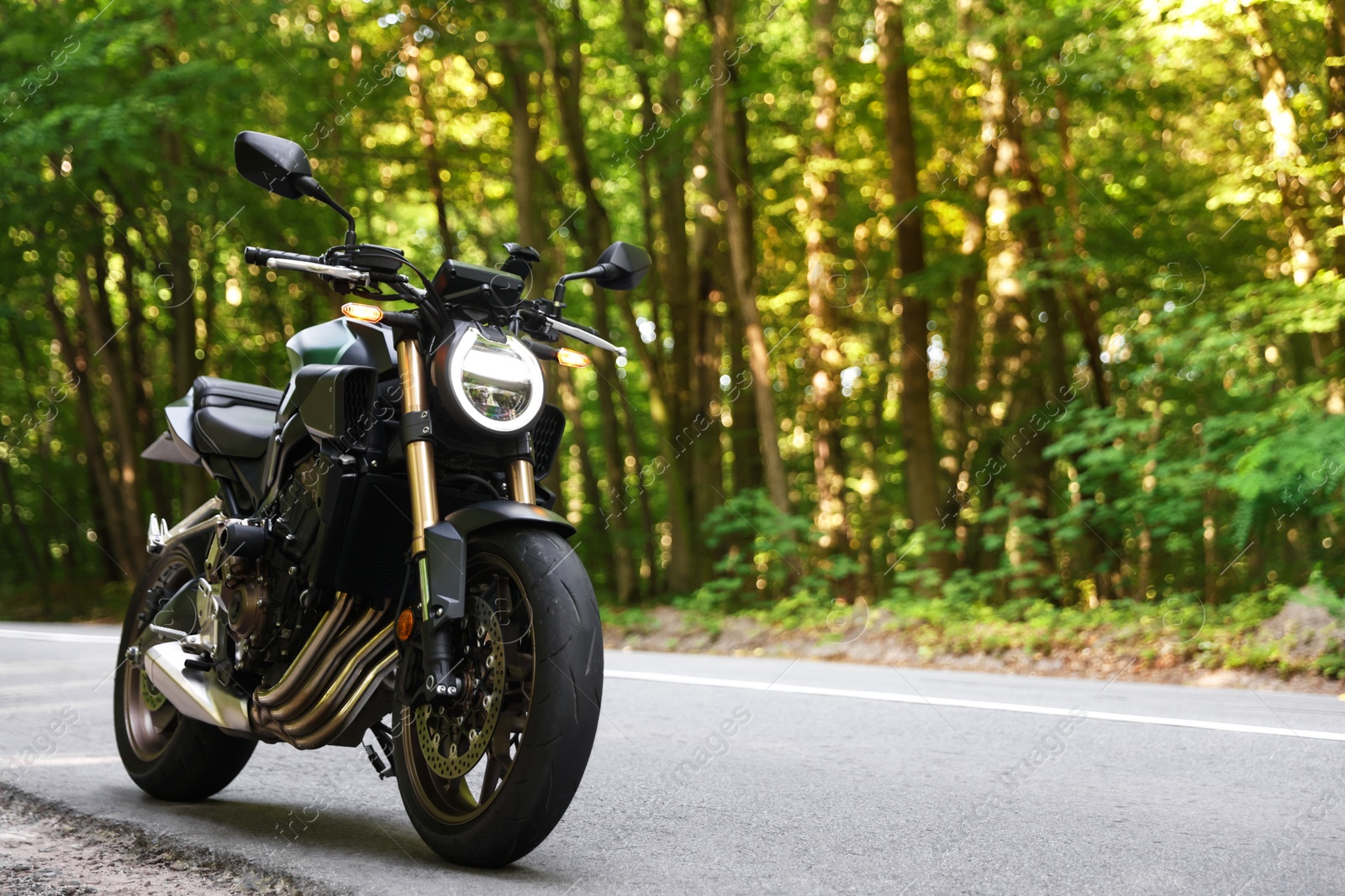 Modern black motorcycle parked on road outdoors. Space for text Photo of Modern black motorcycle parked on road outdoors. Space for text