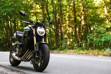 Photo of Modern black motorcycle parked on road outdoors. Space for text