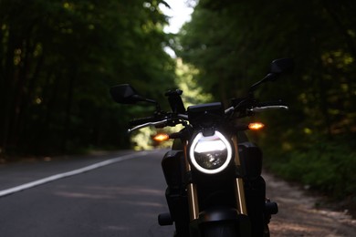 Photo of Modern black motorcycle parked on road outdoors. Space for text