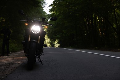 Photo of Modern black motorcycle parked on road outdoors. Space for text