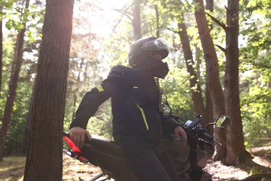 Photo of Young man in helmet with modern motorcycle outdoors