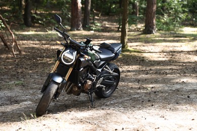 Photo of One modern black motorcycle parked in forest