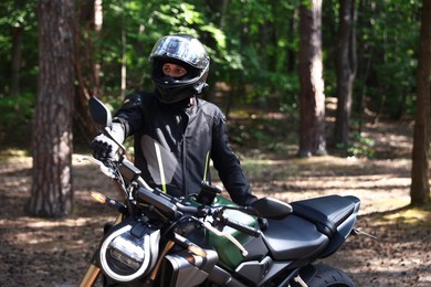 Photo of Young man in helmet with modern motorcycle outdoors