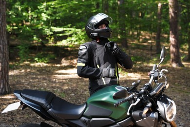 Photo of Young man in helmet with modern motorcycle outdoors