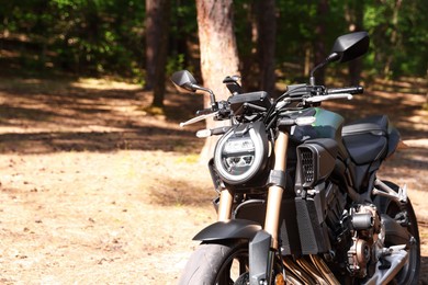 Photo of Modern black motorcycle parked in forest. Space for text