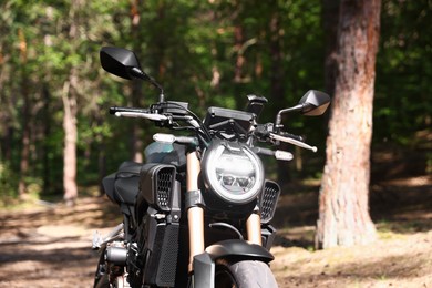 Photo of One modern black motorcycle parked in forest