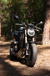 Photo of One modern black motorcycle parked in forest