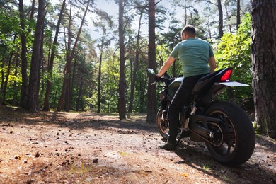 Photo of Young man with modern motorcycle outdoors, back view. Space for text