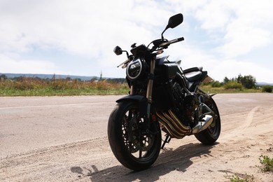 Photo of Modern black motorcycle parked near road outdoors. Space for text