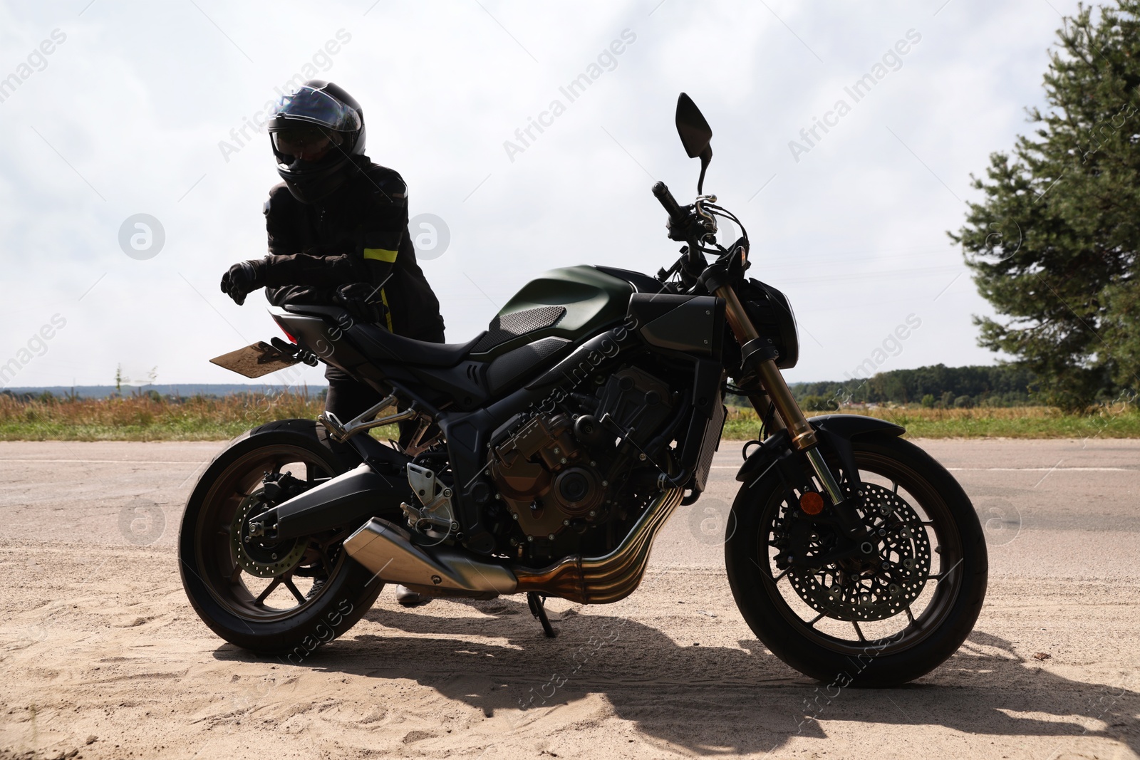 Young man in helmet with modern motorcycle outdoors Photo of Young man in helmet with modern motorcycle outdoors