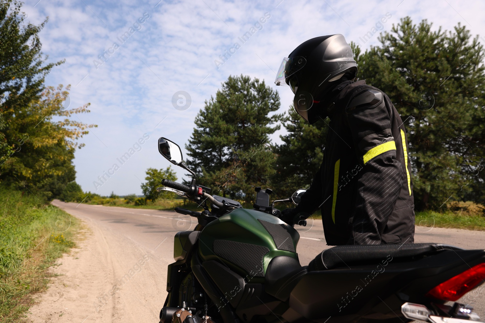 Photo of Young man in helmet with modern motorcycle outdoors, back view. Space for text