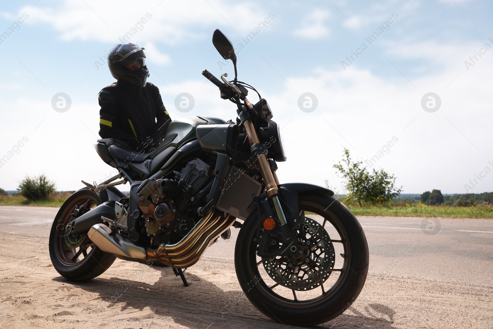 Photo of Young man in helmet with modern motorcycle outdoors