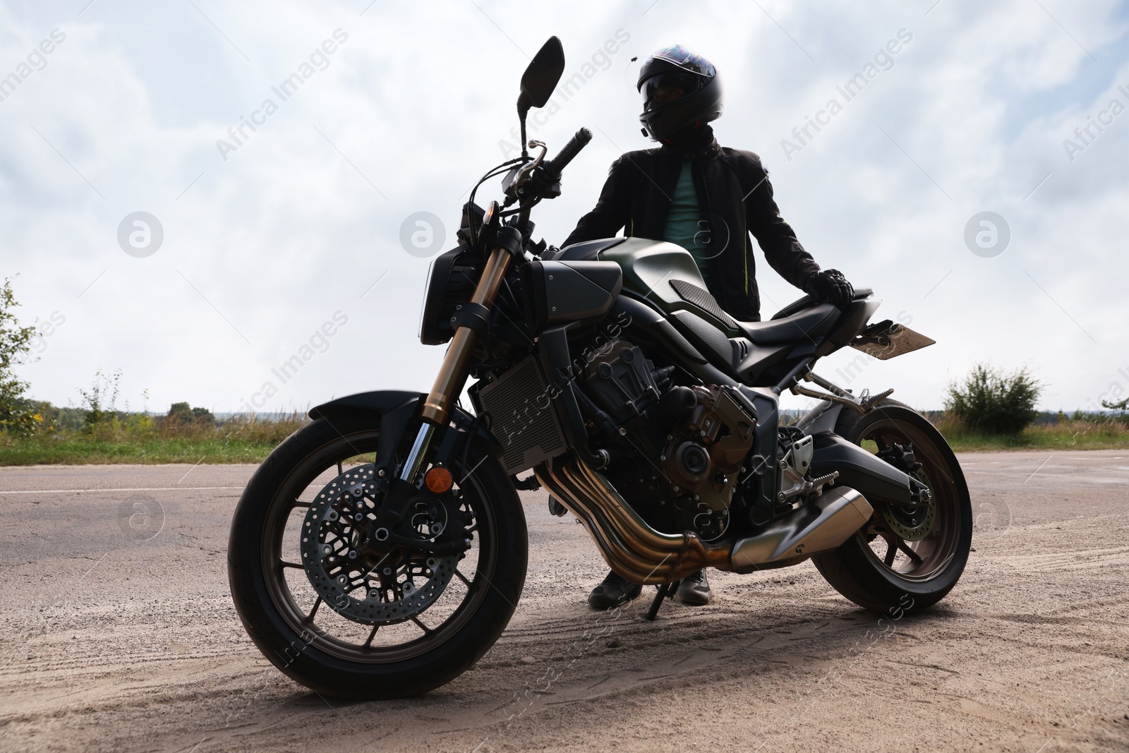 Young man in helmet with modern motorcycle outdoors Photo of Young man in helmet with modern motorcycle outdoors