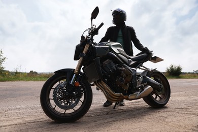 Photo of Young man in helmet with modern motorcycle outdoors