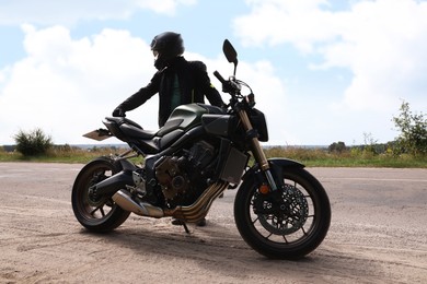 Photo of Young man in helmet with modern motorcycle outdoors