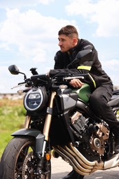 Photo of Handsome young man with modern motorcycle outdoors