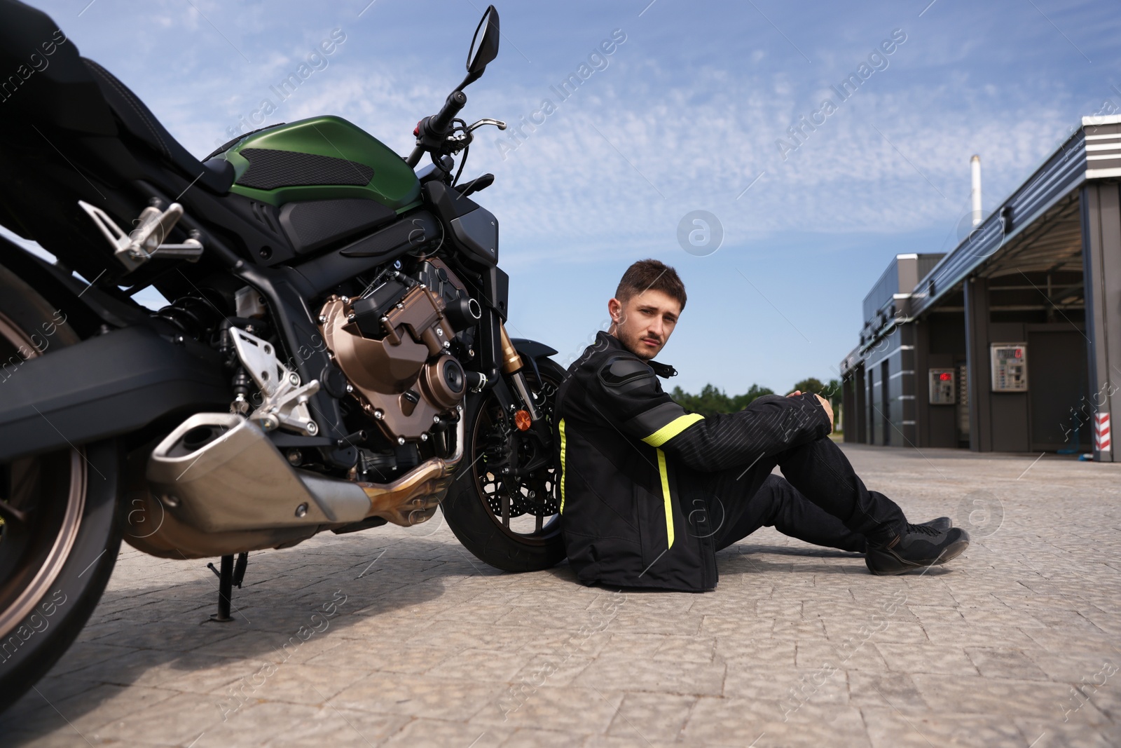 Handsome young man with modern motorcycle outdoors Photo of Handsome young man with modern motorcycle outdoors