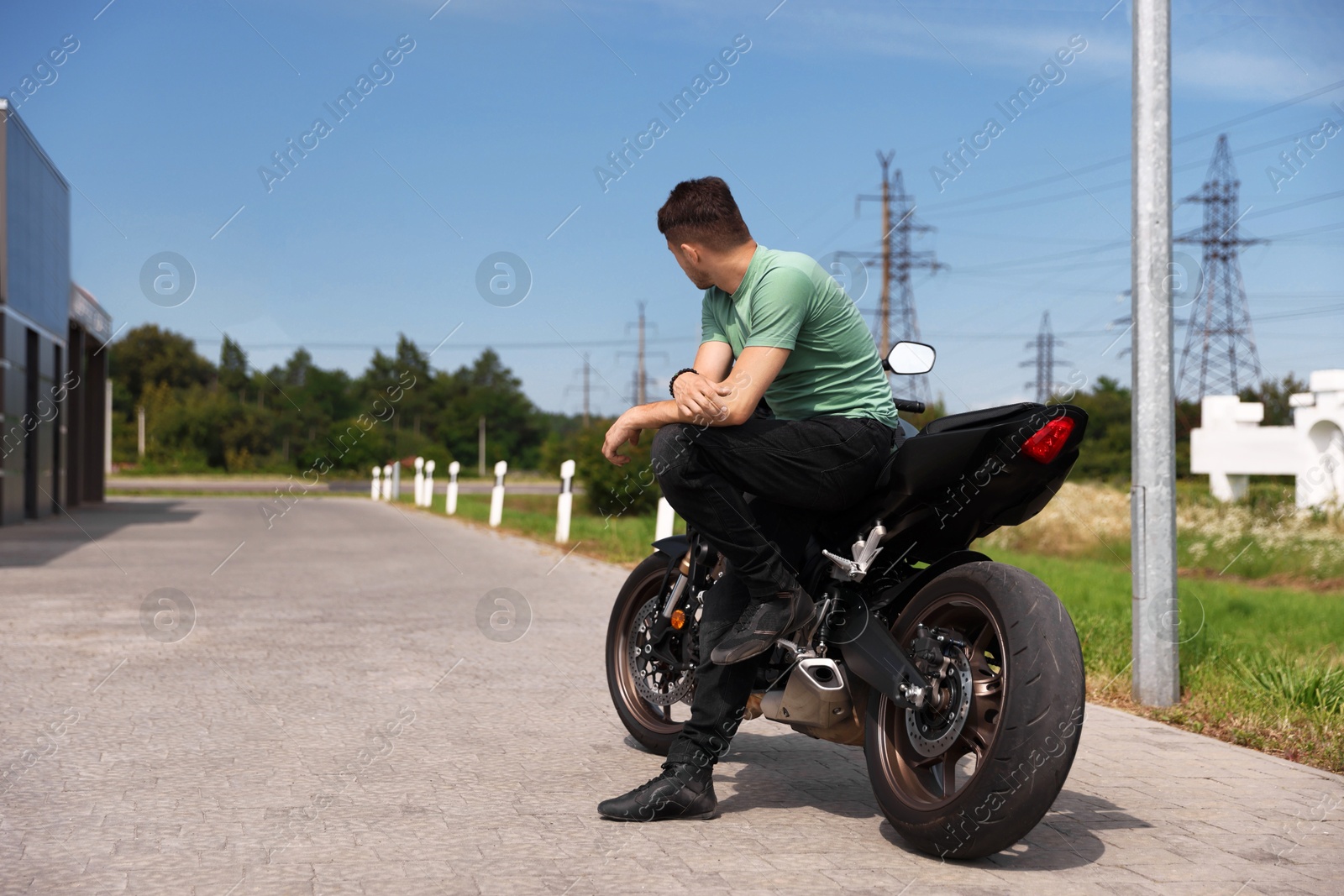 Young man with modern motorcycle near road outdoors. Space for text Photo of Young man with modern motorcycle near road outdoors. Space for text