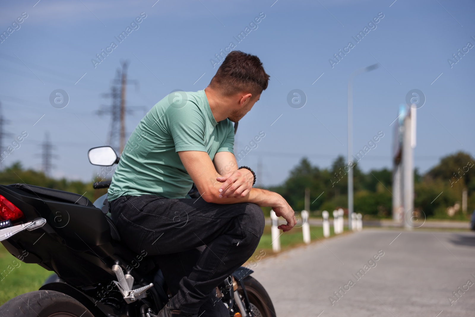 Photo of Young man with modern motorcycle near road outdoors. Space for text
