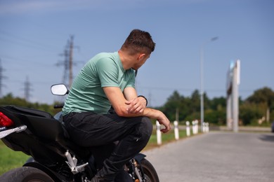 Photo of Young man with modern motorcycle near road outdoors. Space for text