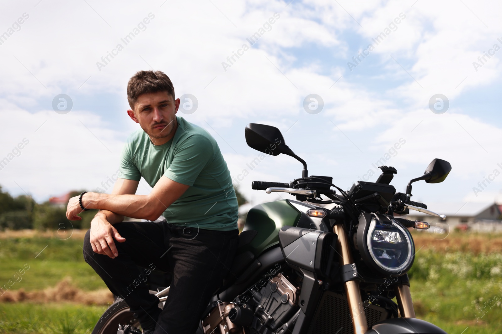Handsome young man with modern motorcycle outdoors Photo of Handsome young man with modern motorcycle outdoors