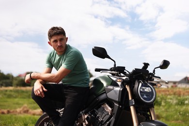 Photo of Handsome young man with modern motorcycle outdoors
