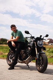 Photo of Handsome young man with modern motorcycle outdoors