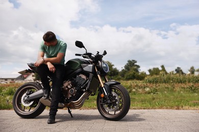 Photo of Handsome young man with modern motorcycle outdoors. Space for text