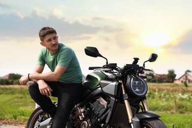 Photo of Handsome young man with modern motorcycle outdoors