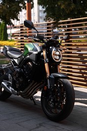Photo of One modern black motorcycle parked near road outdoors
