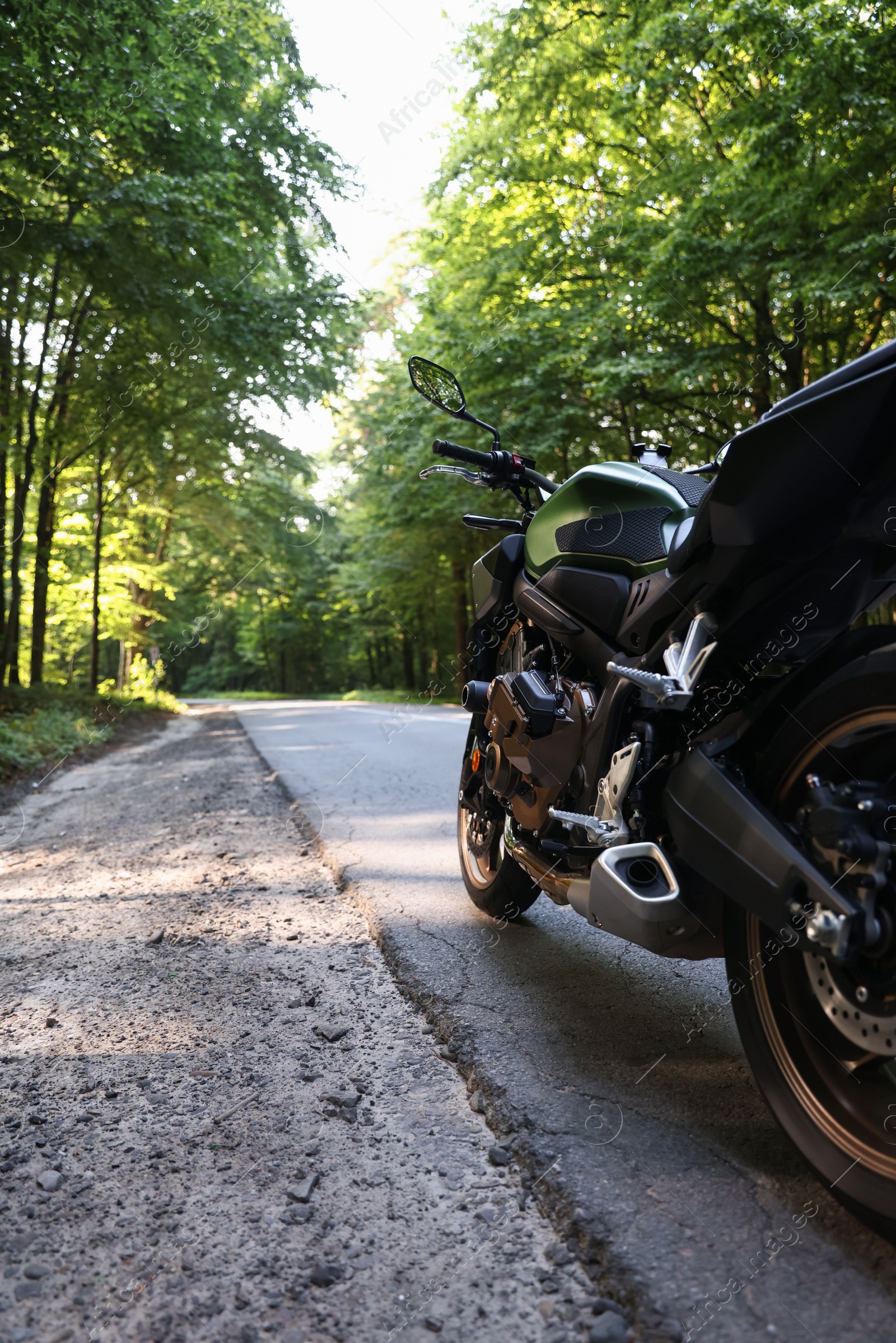 Modern black motorcycle parked on road outdoors Photo of Modern black motorcycle parked on road outdoors