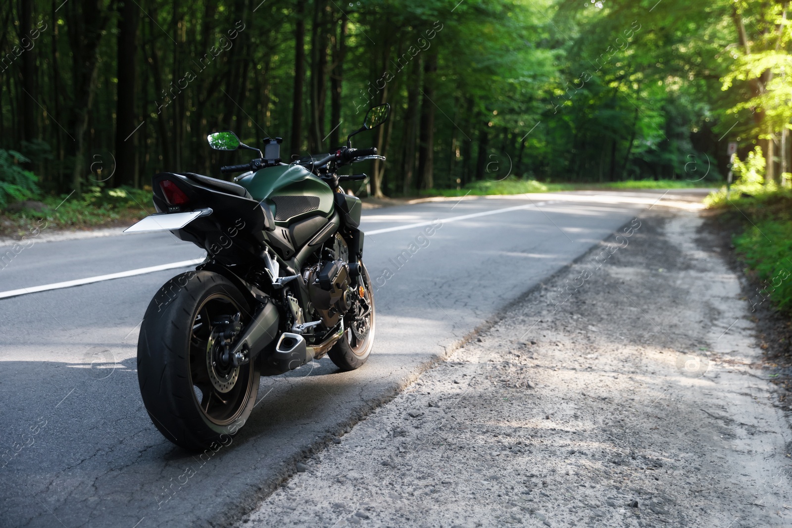 Modern black motorcycle parked on road outdoors. Space for text Photo of Modern black motorcycle parked on road outdoors. Space for text