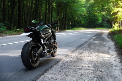 Photo of Modern black motorcycle parked on road outdoors. Space for text