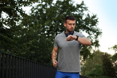 Photo of Athletic young man in sportswear running outdoors, space for text