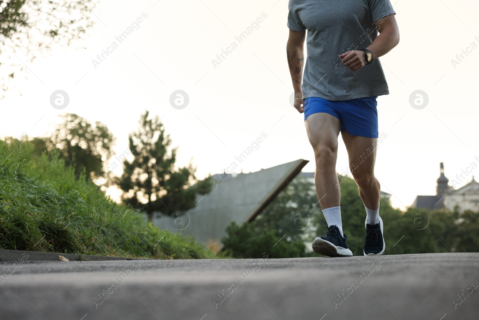 Photo of Athletic young man in sportswear running outdoors, closeup. Space for text