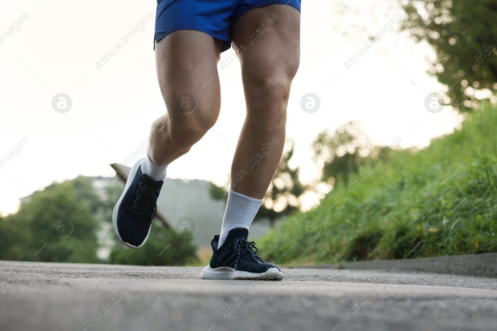 Photo of Athletic young man in sportswear running outdoors, closeup