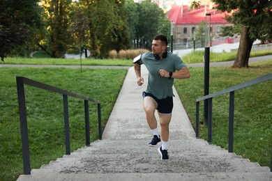 Photo of Athletic young man in sportswear running up stairs outdoors