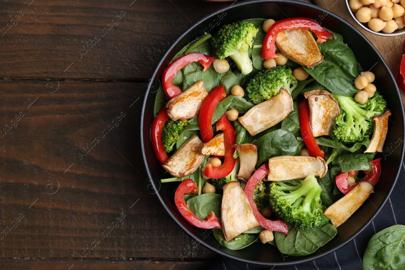 Tasty salad with eryngium mushrooms, chickpeas, vegetables and spinach on wooden table, top view. Space for text Photo of Tasty salad with eryngium mushrooms, chickpeas, vegetables and spinach on wooden table, top view. Space for text