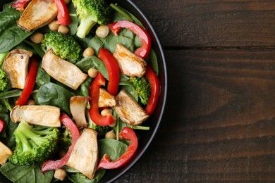 Photo of Tasty salad with eryngium mushrooms, chickpeas, vegetables and spinach on wooden table, top view. Space for text