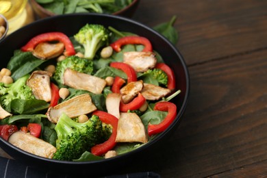 Photo of Tasty salad with eryngium mushrooms, chickpeas, vegetables and spinach on wooden table, closeup. Space for text