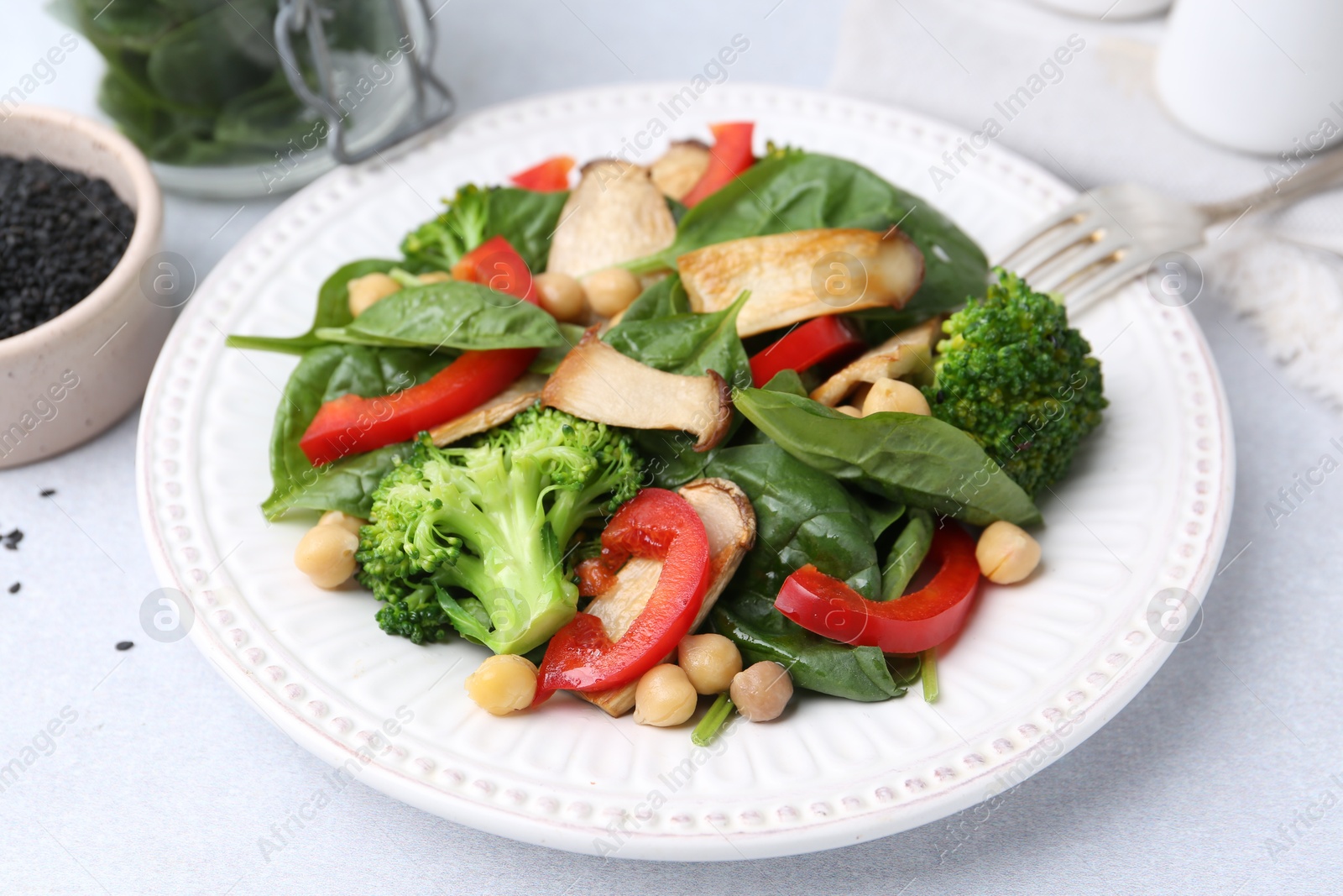 Tasty salad with eryngium mushrooms, chickpeas, vegetables and spinach on light table, closeup Photo of Tasty salad with eryngium mushrooms, chickpeas, vegetables and spinach on light table, closeup