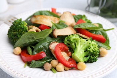 Photo of Tasty salad with eryngium mushrooms, chickpeas, vegetables and spinach on table, closeup
