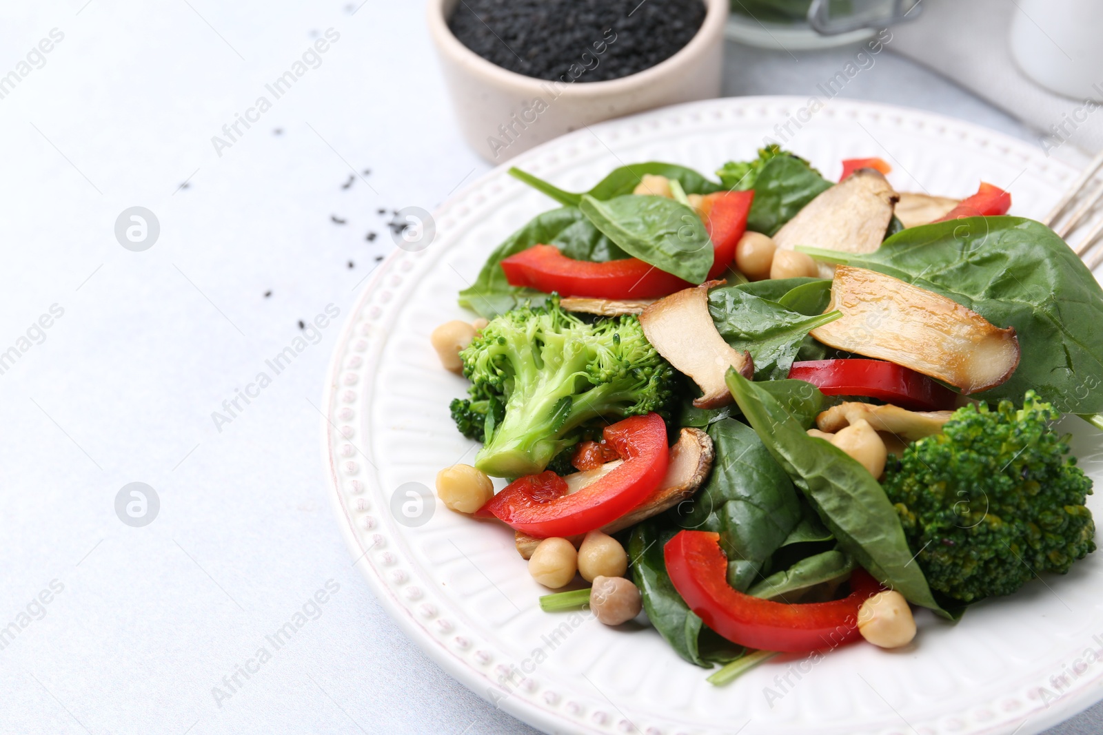 Tasty salad with eryngium mushrooms, chickpeas, vegetables and spinach on light table, closeup. Space for text Photo of Tasty salad with eryngium mushrooms, chickpeas, vegetables and spinach on light table, closeup. Space for text