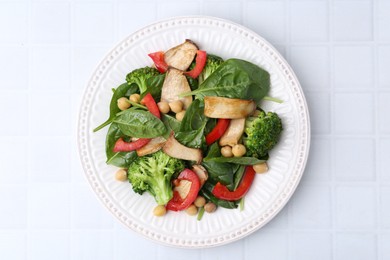 Photo of Tasty salad with eryngium mushrooms, chickpeas, vegetables and spinach on white tiled table, top view