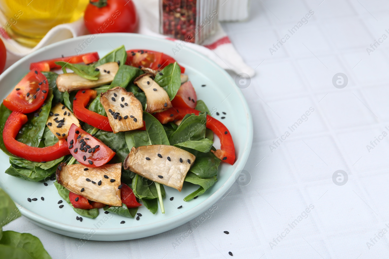 Photo of Tasty salad with eryngium mushrooms served on white tiled table, closeup. Space for text