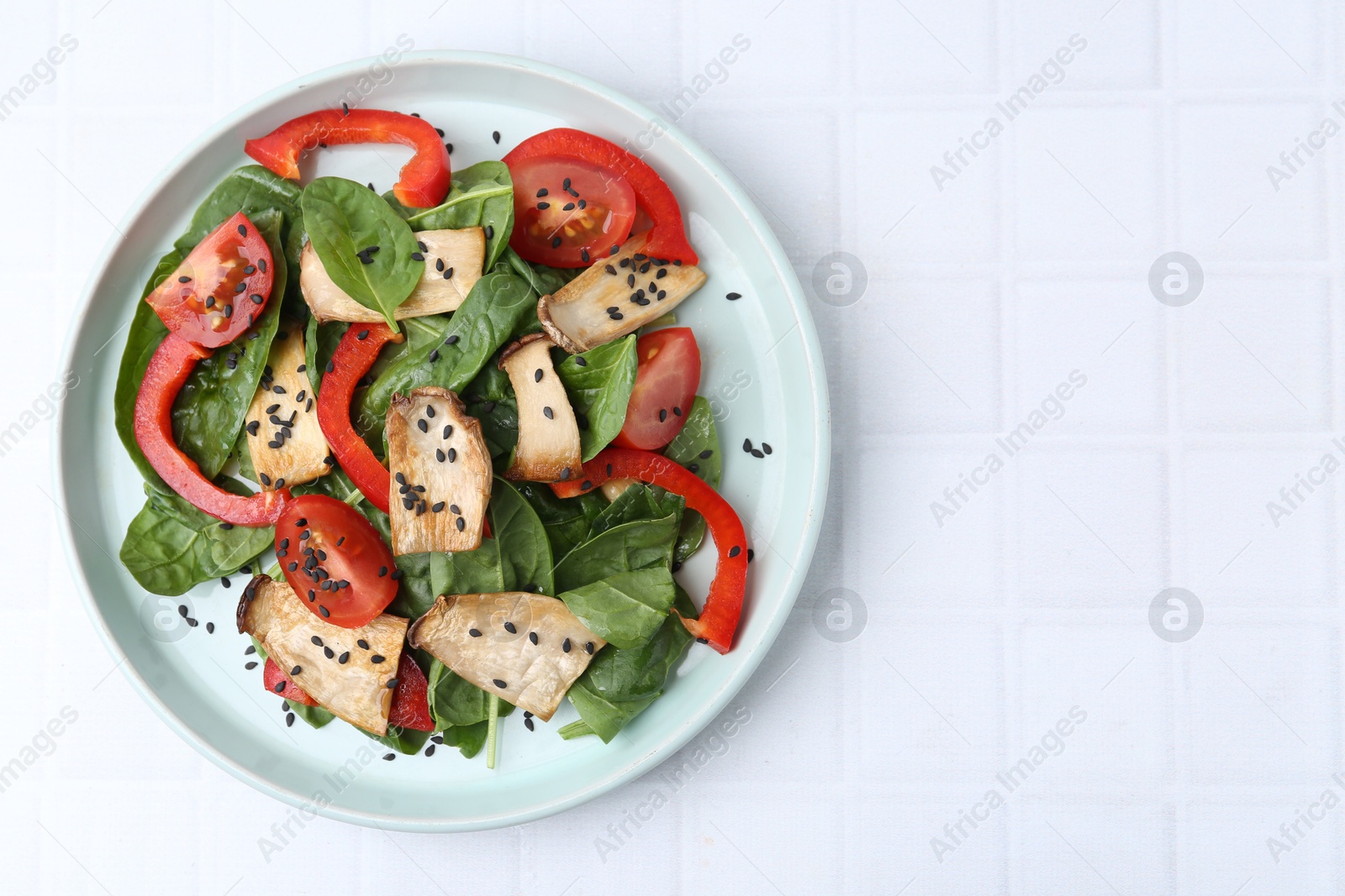 Tasty salad with eryngium mushrooms, vegetables, spinach and sesame on white tiled table, top view. Space for text Photo of Tasty salad with eryngium mushrooms, vegetables, spinach and sesame on white tiled table, top view. Space for text
